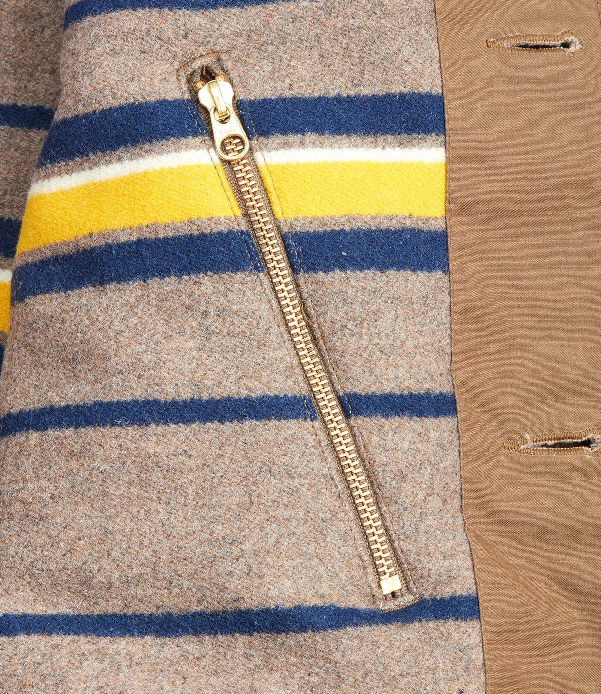 Close-up of the Wool-lined Waxed Field Jacket Tan by Best Made Co., showing wool fabric with blue, white, and yellow stripes, a gold zipper, and tan button placket—classic details of this outerwear.