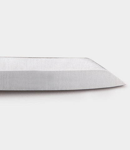 Close-up of the sharp, angled tip of a handmade Mid Brass Higo Knife by Best Made Co., displayed against a plain white background.
