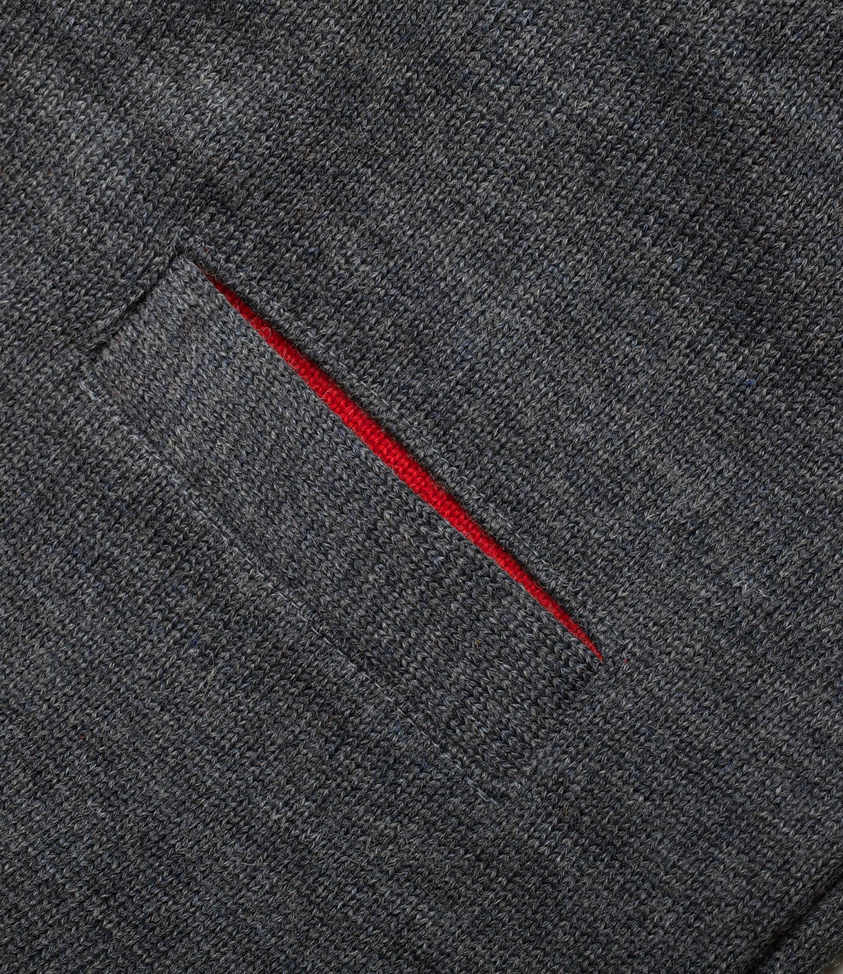 Close-up of a gray Dehen Shawl Neck Sweater in Charcoal by Best Made Co., featuring textured fabric and a welt pocket with red lining—showcasing timeless Portland craftsmanship.