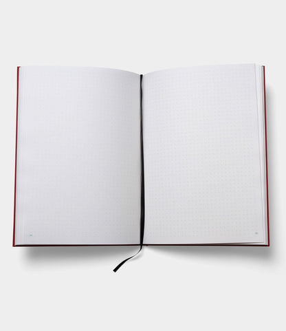 The S.B.T. Max Cloth-Bound Notebook by Best Made Co. lies open flat, revealing white dotted pages edged in red and a black ribbon bookmark at the center—blank and ready for writing or drawing.